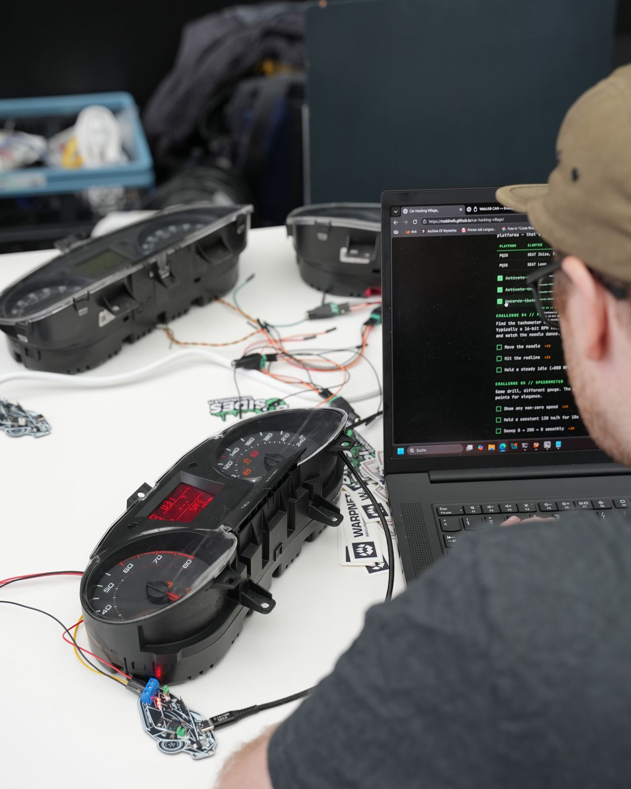 Close-up of a Škoda Fabia cluster powered up on a bench, speedometer needle visible, next to a laptop running the WebUSB CAN console.